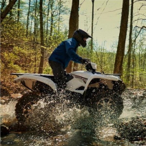 Rider driving through a puddle in the woods on a Yamaha Grizzly
